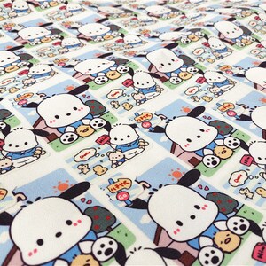 May include: White fabric with a repeating pattern of a cartoon dog wearing a blue shirt and holding a soccer ball. The dog is standing in front of a pink doghouse with a white roof. The fabric has a white background with a light blue border around each dog.