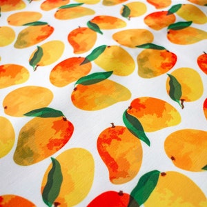May include: A white fabric with a repeating pattern of yellow and orange mangoes. The mangoes are painted in a watercolor style with green leaves.
