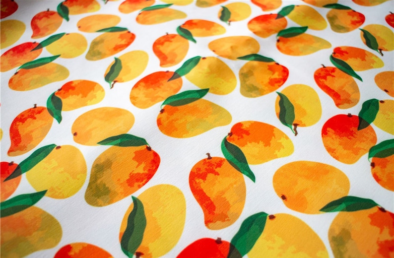 May include: A white fabric with a repeating pattern of yellow and orange mangoes. The mangoes are painted in a watercolor style with green leaves.