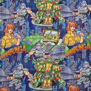 Peut inclure: Motif répété avec des personnages de la franchise Teenage Mutant Ninja Turtles. Le motif comprend les tortues, Shredder, April O'Neil et un véhicule sur le thème des tortues, sur fond de paysage urbain. Le mot "COWABUNGA" est également présent.