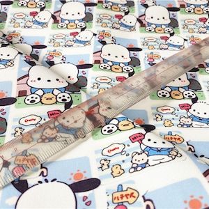 May include: White fabric with a repeating pattern of a cartoon dog wearing a blue shirt and holding a yellow chick. The dog is surrounded by a blue and white border with the words "Chubby" and "Hi-m" in a speech bubble. The fabric is measured with a ruler in inches.
