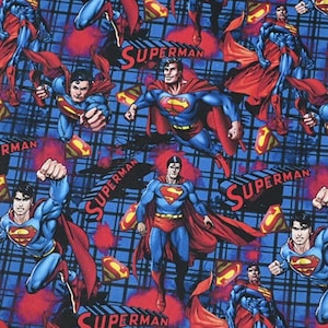 Puede incluir: Tela azul con un patrón repetido de ilustraciones de Superman. Las imágenes muestran a Superman con su icónico traje azul y rojo, con el logotipo de Superman visible. La palabra "Superman" también está impresa en la tela.