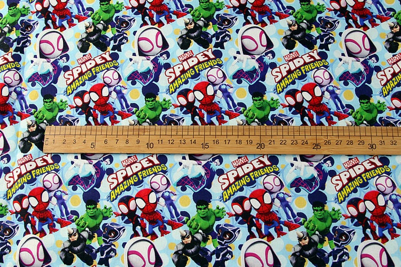 May include: A blue fabric with a repeating pattern of Marvel's Spidey and his Amazing Friends characters. The characters include Spider-Man, Miles Morales, Ghost-Spider, Hulk, and Black Panther. The fabric has a white background with yellow polka dots.