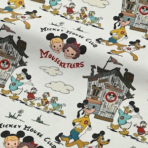 Peut inclure: Tissu blanc avec un motif répété de personnages du Mickey Mouse Club. Le motif comprend Mickey Mouse, Donald Duck, Dingo et les Mouseketeers, ainsi que des bâtiments stylisés et du texte. La palette de couleurs est principalement des couleurs primaires sur fond blanc.