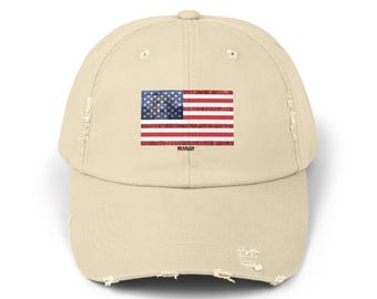 May include: A beige distressed baseball cap with a vintage American flag design. The flag is red, white, and blue with a distressed look. The text "BEAGLES" is printed below the flag.