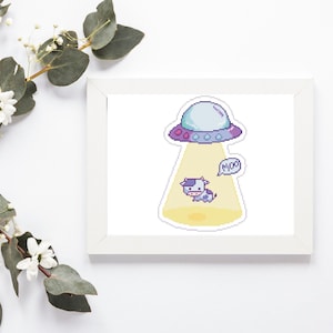May include: A framed print featuring a pixelated illustration of a cow being beamed up by a UFO. The UFO is light blue and purple, and the cow is purple and white. A speech bubble says "Moo".