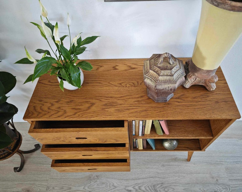 May include: A wooden cabinet with four drawers and a shelf. The cabinet has a light brown finish and is decorated with a small, decorative pot and a ceramic box.