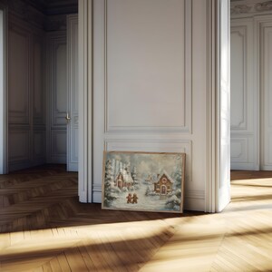 May include: A framed winter landscape painting featuring snow-covered houses and trees. The artwork depicts a cozy village scene with figures walking in the snow. The painting is set against a backdrop of a cloudy sky, creating a serene and festive atmosphere.