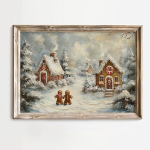 May include: A framed painting depicts a winter scene with snow-covered gingerbread houses and trees. Two gingerbread people stand on a snowy path. The artwork has a warm, inviting feel with soft colors and a rustic wooden frame.