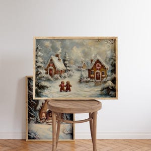 May include: A framed winter landscape painting featuring snow-covered gingerbread houses and two gingerbread people. The artwork has a warm, inviting color palette with a wooden frame, evoking a cozy holiday theme. The painting is displayed on a wooden stool.