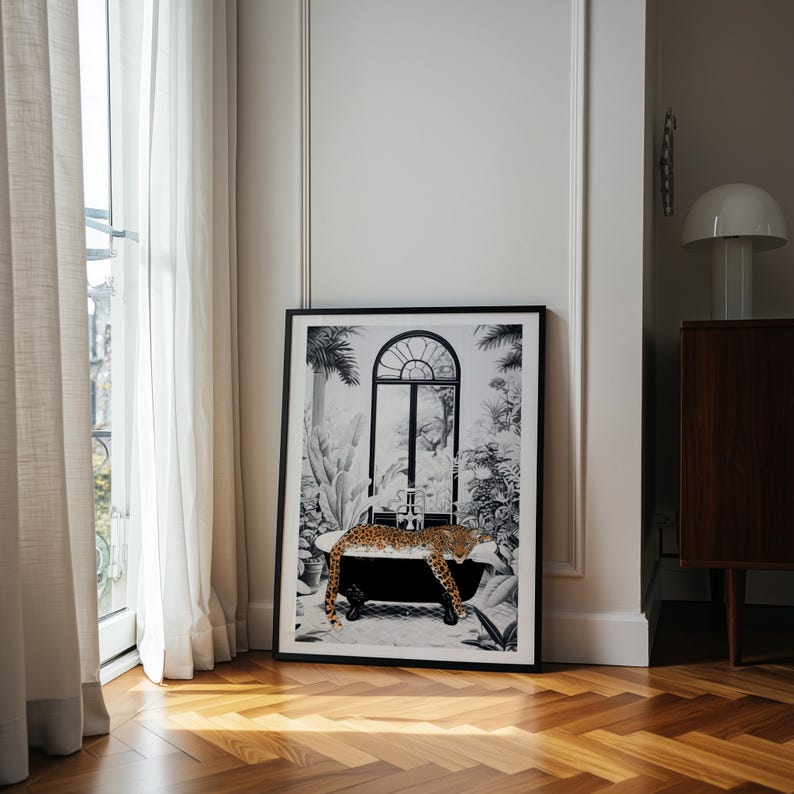 May include: A framed rectangular wall art print featuring a black and white illustration of a bathtub in a tropical setting with a leopard resting inside. The leopard has a spotted orange and brown coat, contrasting with the monochrome background.