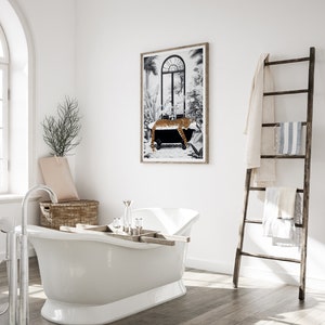 May include: A framed wall art print featuring a black and white illustration of a leopard resting in a clawfoot bathtub surrounded by tropical plants, displayed in a bathroom with a white freestanding tub and a wooden towel ladder.