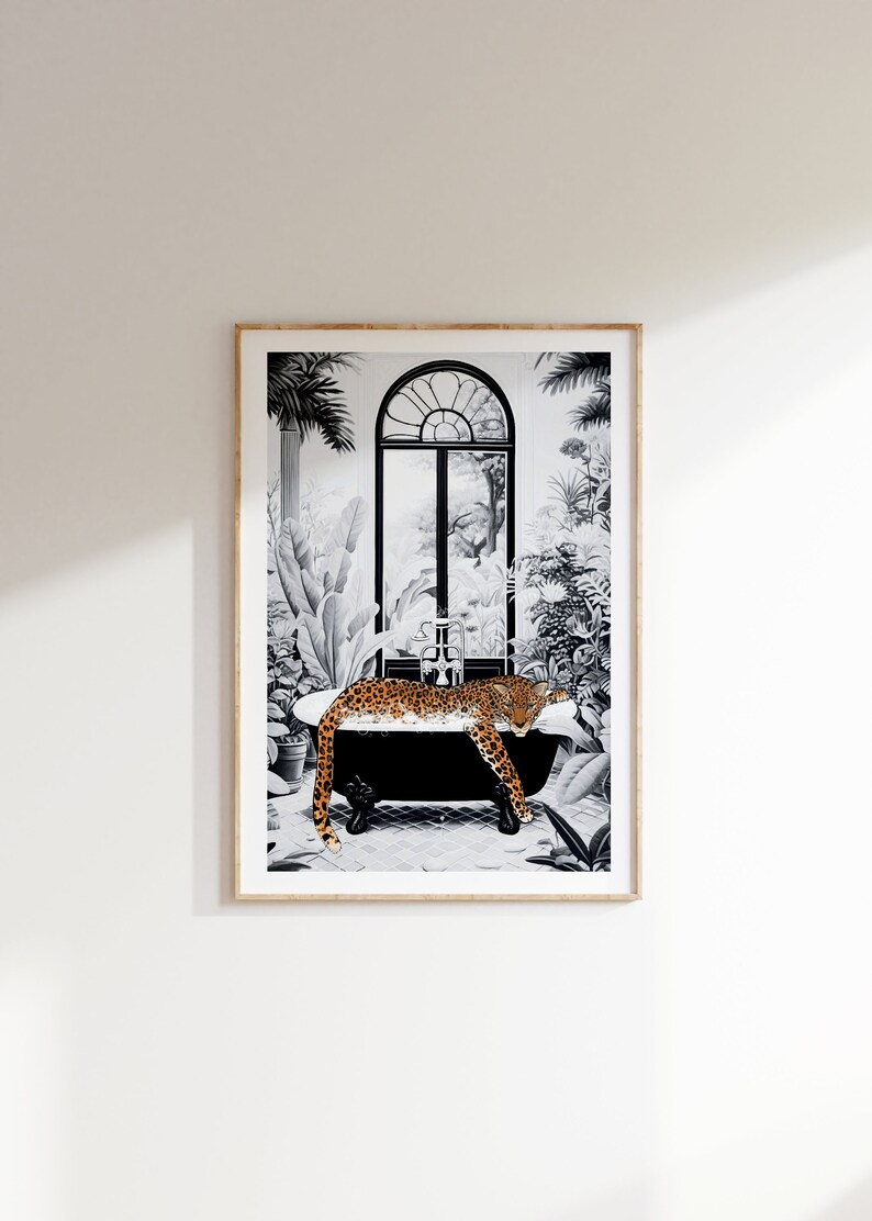 May include: A framed wall art print featuring a black and white illustration of a clawfoot bathtub in a lush, tropical setting. A spotted orange and black leopard rests inside the tub, which is surrounded by various plants and a large arched window.