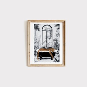 May include: A framed art print featuring a black and white illustration of a leopard resting in a clawfoot bathtub. The scene is set against a backdrop of lush tropical plants and a large arched window, with the leopard's orange and black spotted fur providing a vibrant contrast to the monochrome surroundings.