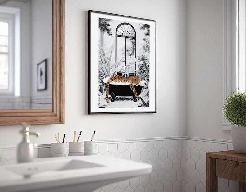 May include: A framed wall art print featuring a black and white illustration of a leopard resting in a clawfoot bathtub. The scene includes tropical plants and an arched window in the background. The leopard has a spotted orange and black coat.