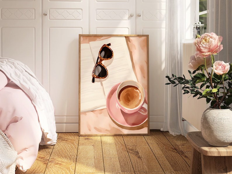 May include: A framed print of a still life featuring a cup of coffee, sunglasses, and an open book on a pink background.