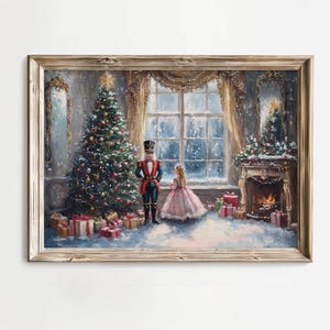 以下が含まれることがあります： 額縁に入ったクリスマスのシーンの絵。装飾されたクリスマスツリーが暖炉の近くに立っており、くるみ割り人形とピンクのドレスを着た女の子がいます。プレゼントはツリーの下にあります。部屋には雪景色を望む大きな窓があります。