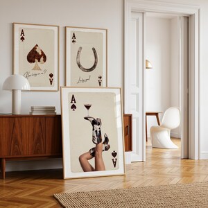 Pode incluir: Tr&ecirc;s impress&otilde;es de arte emolduradas com temas de cartas de baralho. Uma mostra uma p&aacute;, outra uma ferradura e a terceira retrata pernas com botas de cowboy segurando um coquetel. As impress&otilde;es t&ecirc;m uma est&eacute;tica vintage com o texto "How lucky are we?" e "Lucky you!"