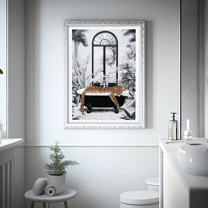 May include: A framed wall art print featuring a black and white illustration of a leopard resting in a black clawfoot bathtub. The scene includes a large arched window and lush tropical foliage. The frame is silver with a decorative textured border.