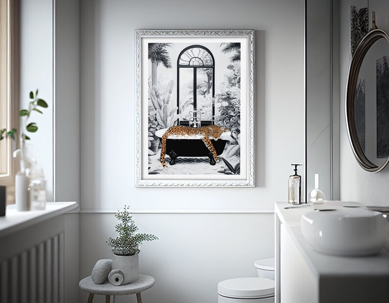 May include: A framed wall art print featuring a black and white illustration of a leopard resting in a black clawfoot bathtub. The scene includes a large arched window and lush tropical foliage. The frame is silver with a decorative textured border.