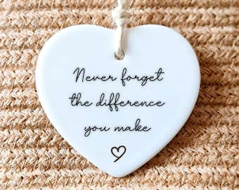May include: White ceramic heart-shaped ornament with the text "Never forget the difference you make" and a small heart symbol.