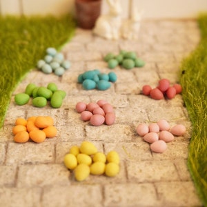 Peut inclure: Une collection d'œufs de Pâques colorés dans différentes nuances de bleu, vert, rose, orange et jaune. Les œufs sont disposés en rangées sur un chemin de pierre.