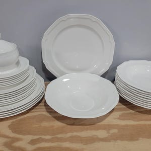 May include: A white ceramic mug with a black handle and the text "But First, Coffee" in a black, handwritten-style font. The mug is on a white surface.