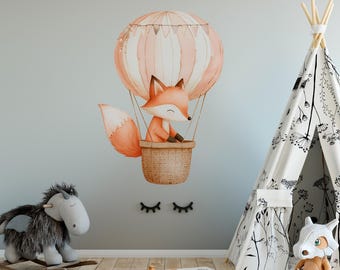 May include: A cute orange fox in a hot air balloon with pink and white stripes. The balloon is decorated with small flags. The fox is sitting in a wicker basket. The image is a wall decal for a child's room.