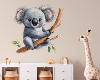May include: A watercolor illustration of a koala sitting on a branch with green leaves. The koala is gray and has a cute expression. The background is a light beige wall.
