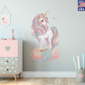 Pode incluir: Um autocolante de parede com um unicórnio com chifre e cascos dourados, em pé sobre nuvens em tons pastel. O unicórnio tem uma crina e cauda fluidas em tons de rosa, roxo e azul. Estrelas douradas complementam o design.