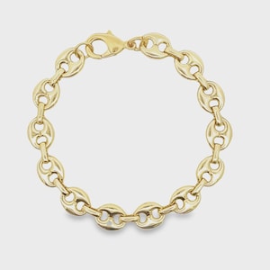 May include: A gold-colored bracelet featuring a series of interconnected, bean-shaped links. The bracelet has a lobster clasp closure. The jewelry is displayed against a neutral background, highlighting its polished, reflective surface.