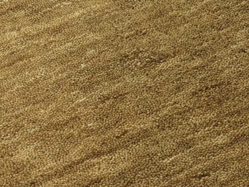 Op de afbeelding: Close-up van een textuurrijke, bruine stof met een subtiel diagonaal patroon. De stof heeft een zachte, pluche textuur.