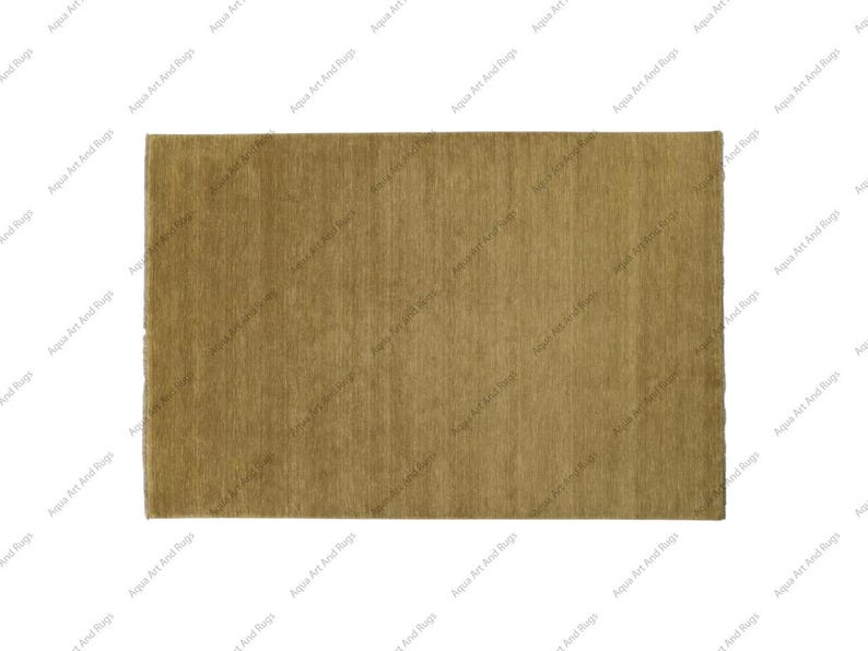 Op de afbeelding: Een effen, lichtbruin tapijt met een subtiel, textuurpatroon. Het tapijt is gemaakt van een zacht, pluche materiaal en heeft een licht vervaagde uitstraling.
