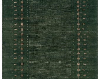 Puede incluir: Una alfombra rectangular verde oscuro con un borde detallado y un diseño central. El borde presenta un patrón repetitivo de cuadrados y formas estilizadas de árboles. El campo central de la alfombra tiene una apariencia texturizada.