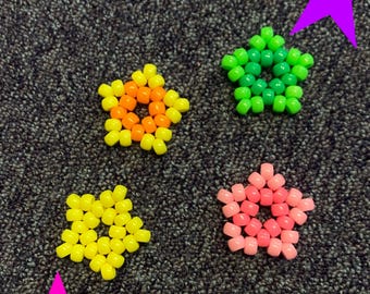Può includere: Quattro braccialetti kandi a forma di stella di colore giallo, arancione, verde e rosa. Il testo "Kandi mystery box!! x3" e "Stars" è visibile nell'immagine.