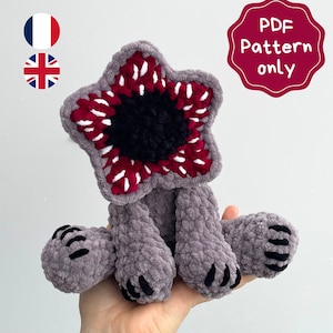 May include: A handmade plush toy in the shape of a Demogorgon, featuring a star-shaped head with red and white details, a black center, and gray body. The text "PDF Pattern only" is visible.