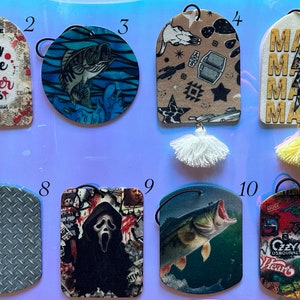 May include: Twelve different car air fresheners with various designs and colors. The designs include a black and pink lightning bolt pattern, a coffee mug with the text "I run on coffee and murder shows", a blue and white fish, a brown and white pattern with a book and a football, a yellow and black pattern with the text "Mama", a white and pink pattern with the text "Fueled by iced coffee and anxiety", a black and white camera pattern, a gray diamond pattern, a black and white pattern with a scary face, a blue and white fish, a red and white pattern with the text "Cizzy Heart", and a black and white pattern with the text "I'd rather be fishing".