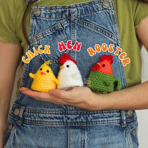 May include: Three crocheted chicken figures: a yellow chick, a white hen, and a green and red rooster. The text "Chick Hen Rooster" is above the figures. The figures are held in a person's hand, against a denim background.