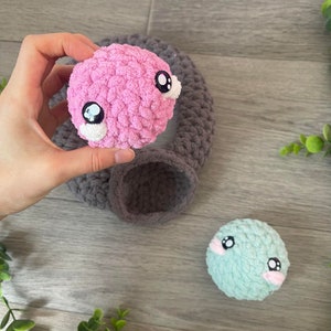 May include: Two crocheted stuffed toys with big eyes. One is pink and the other is light blue.