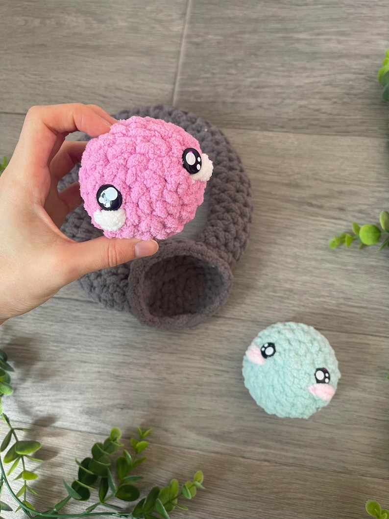 May include: Two crocheted stuffed toys with big eyes. One is pink and the other is light blue.