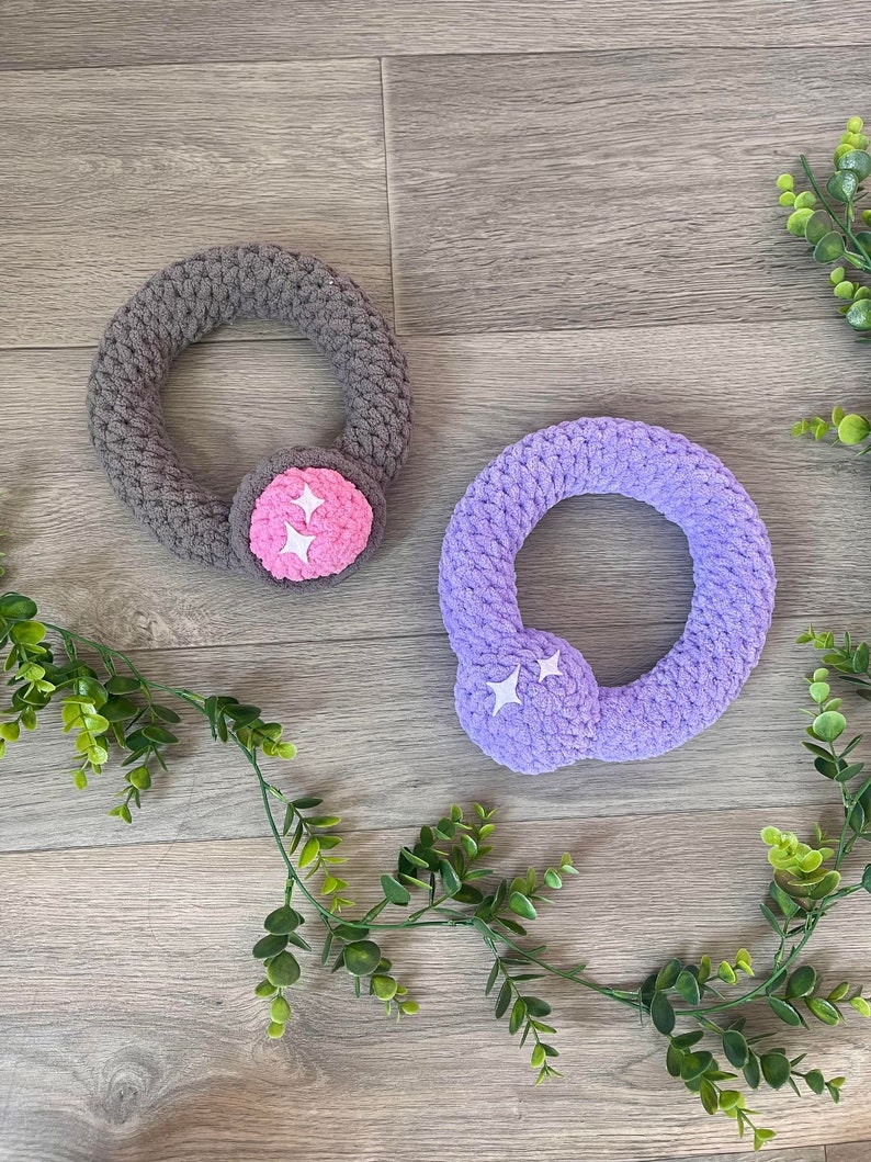 May include: Two crocheted rings with star-shaped embellishments. One ring is gray and the other is purple.