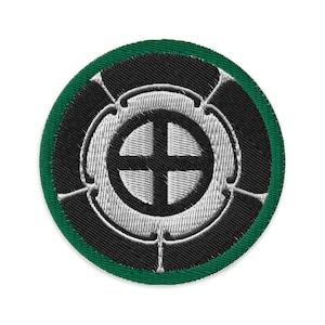 Peut inclure: Un écusson brodé noir et blanc avec une bordure verte. L'écusson représente une croix stylisée à l'intérieur d'un cercle.