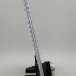 Może przedstawiać: Przezroczysta plastikowa gablota z czarnym stojakiem. Stojak ma okrągłą podstawę z białym i czerwonym wzorem.