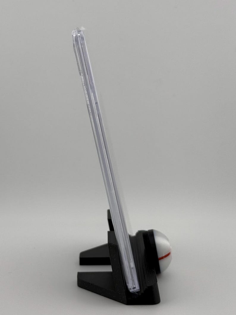 Może przedstawiać: Przezroczysta plastikowa gablota z czarnym stojakiem. Stojak ma okrągłą podstawę z białym i czerwonym wzorem.