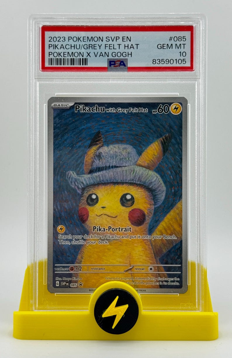 Może przedstawiać: Karta kolekcjonerska Pokemon przedstawiająca Pikachu w szarym filcowym kapeluszu. Karta znajduje się w ochronnym etui z oceną Gem Mint 10. Karta pochodzi z zestawu 2023 Pokemon SVP EN i nosi tytuł "Pikachu with Grey Felt Hat". Karta posiada umiejętność Pika-Portrait, kt&oacute;ra pozwala graczowi przeszukać sw&oacute;j talia w poszukiwaniu Pikachu i umieścić go na swojej ławce.
