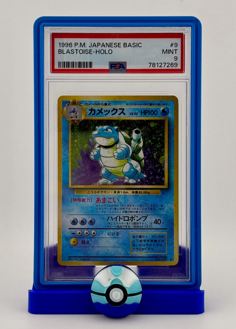 Może przedstawiać: Karta Pokemon Blastoise, niebieskiego Pokemona ż&oacute;łwia z pancerzem, oceniona przez PSA w ochronnym etui. Karta pochodzi z japońskiego podstawowego zestawu z 1996 roku i została oceniona na 9, co oznacza, że jest w idealnym stanie.