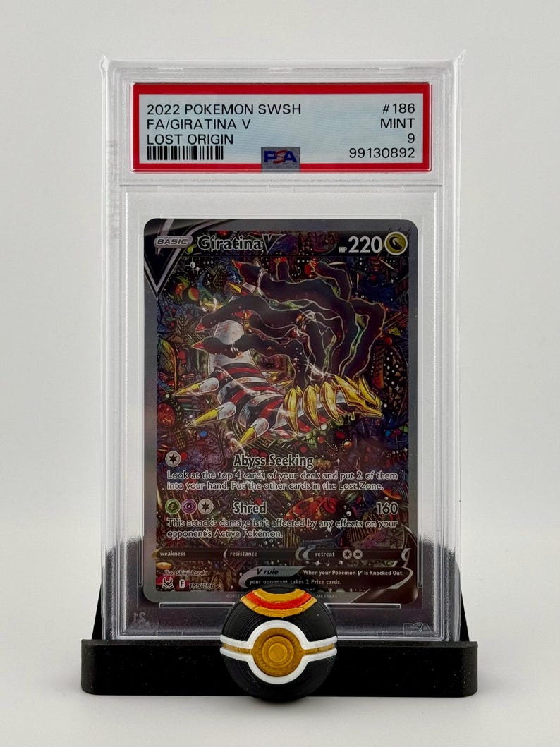Może przedstawiać: Karta Pok&eacute;mon Giratina V z zestawu Lost Origin, oceniona przez PSA. Karta jest w idealnym stanie i ma ocenę 9. Karta jest podstawową kartą Pok&eacute;mona z 220 PW. Karta ma dwa ataki: Abyss Seeking i Shred. Karta jest otoczona czarno-białym tłem.