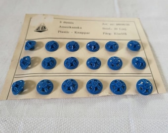 Blue vintage buttons, open bottom design with flower in the middle. 18 buttons, american. Swedish text. 20 Line/1.1 cm.