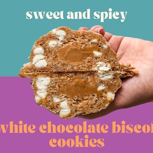 May include: A hand holds a split open cookie with a sweet and spicy white chocolate biscoff filling. The cookie is brown and has white chocolate chips in it. The text "sweet and spicy" is above the cookie and the text "white chocolate biscoff cookies" is below the cookie.