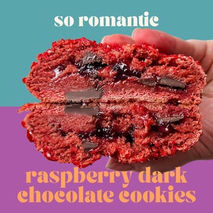 May include: A close-up of a red raspberry and dark chocolate cookie, split in half, showing the gooey raspberry filling and chocolate chips inside. The text "so romantic" is above the cookie and "raspberry dark chocolate cookies" is below.